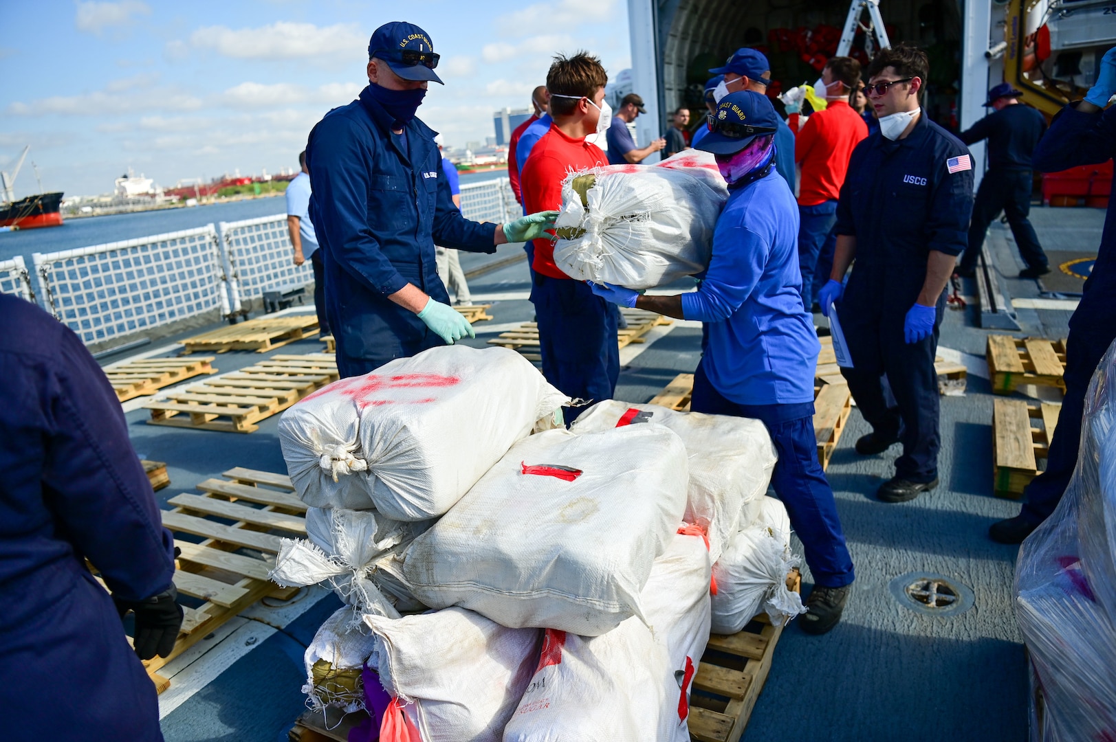 USCGC Mohawk (WMEC 913) crew members stack bales of illegal narcotics on the flight deck of the cutter