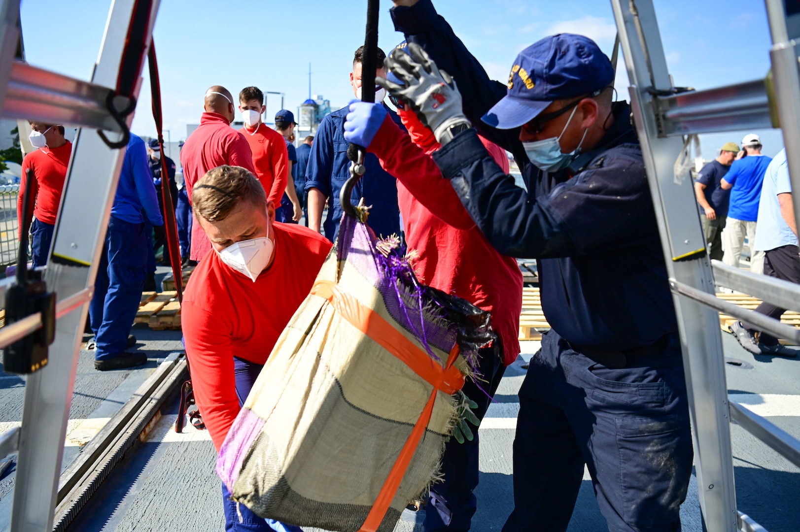 USCGC Mohawk (WMEC 913) crew members use a pulley system to bring up illegal narcotics from below deck during a drug offload.