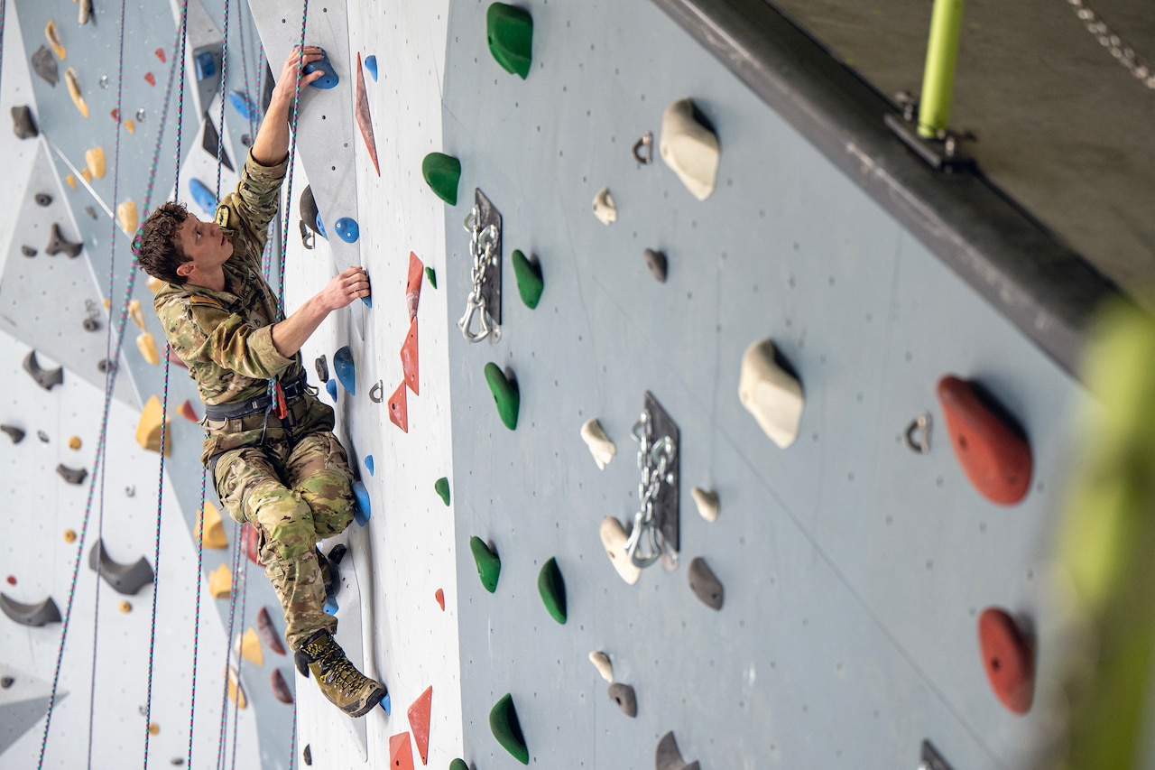 A man climbs toward the top of a rock wall.