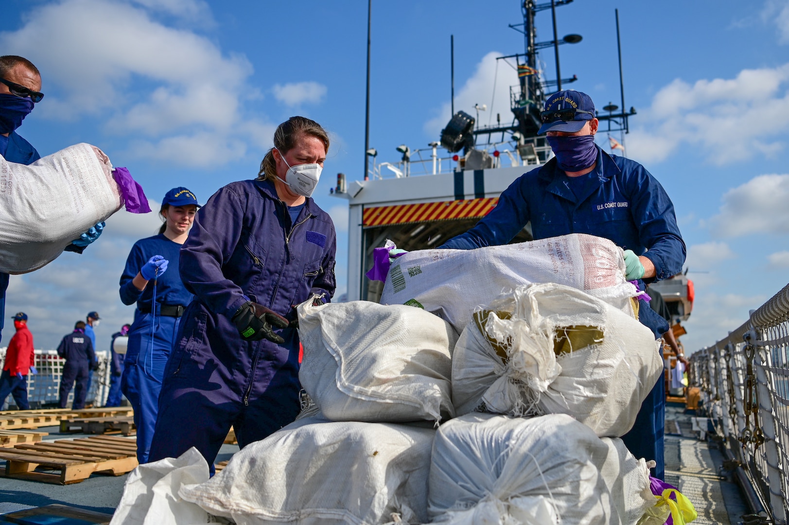 U.S. Coast Guard Cutter Mohawk (WMEC-913) crewmembers pose with approximately 18,000 pounds of illegal narcotics at Port Everglades in Fort Lauderdale, Florida, May 10, 2025. The Mohawk is homeported in Key West, Florida. (U.S. Coast Guard photo by Petty Officer 2nd Class Ryan Estrada)
