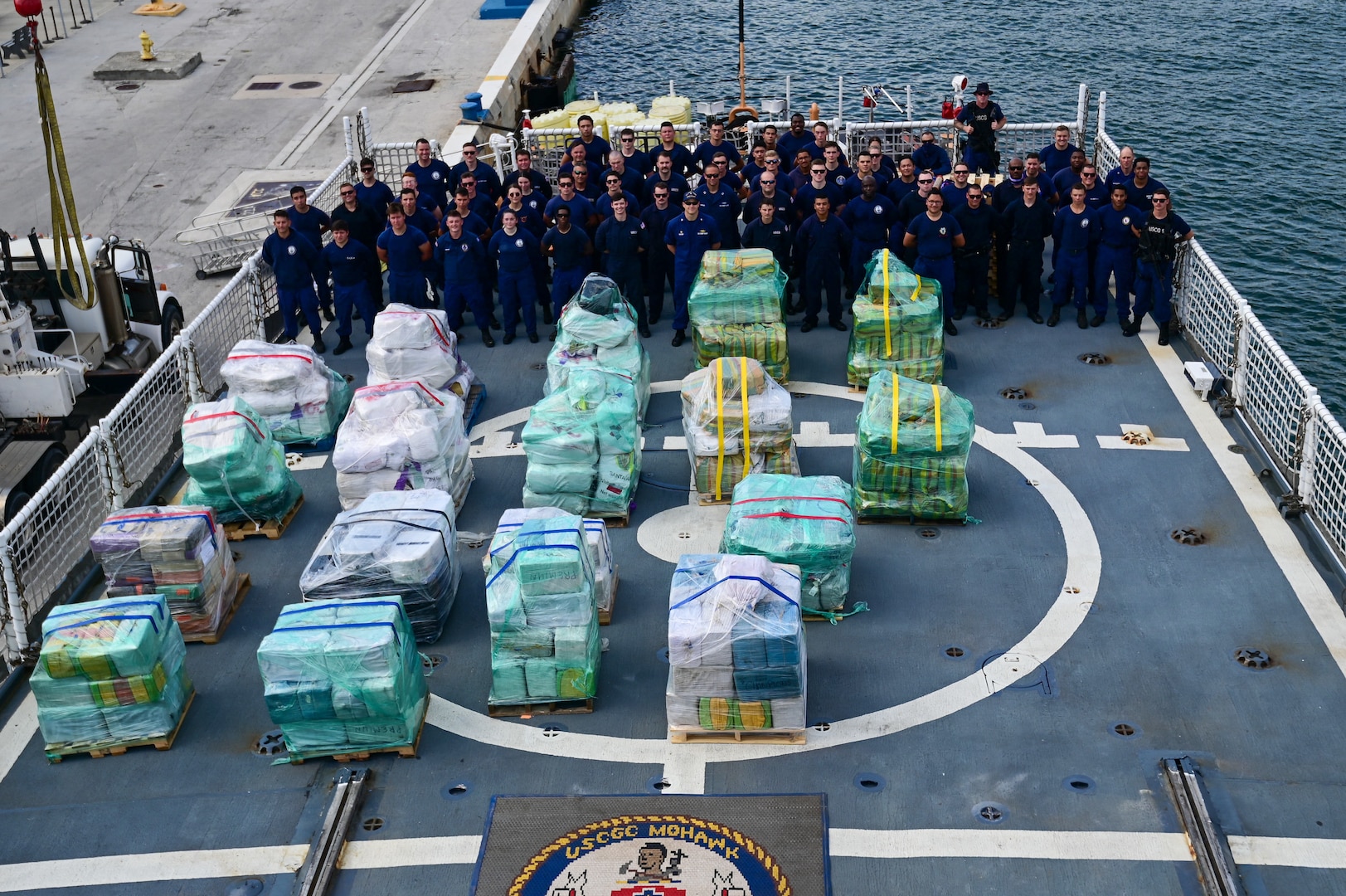 U.S. Coast Guard Cutter Mohawk (WMEC-913) crewmembers pose with approximately 18,000 pounds of illegal narcotics at Port Everglades in Fort Lauderdale, Florida, May 10, 2025. The Mohawk is homeported in Key West, Florida. (U.S. Coast Guard photo by Petty Officer 2nd Class Ryan Estrada)