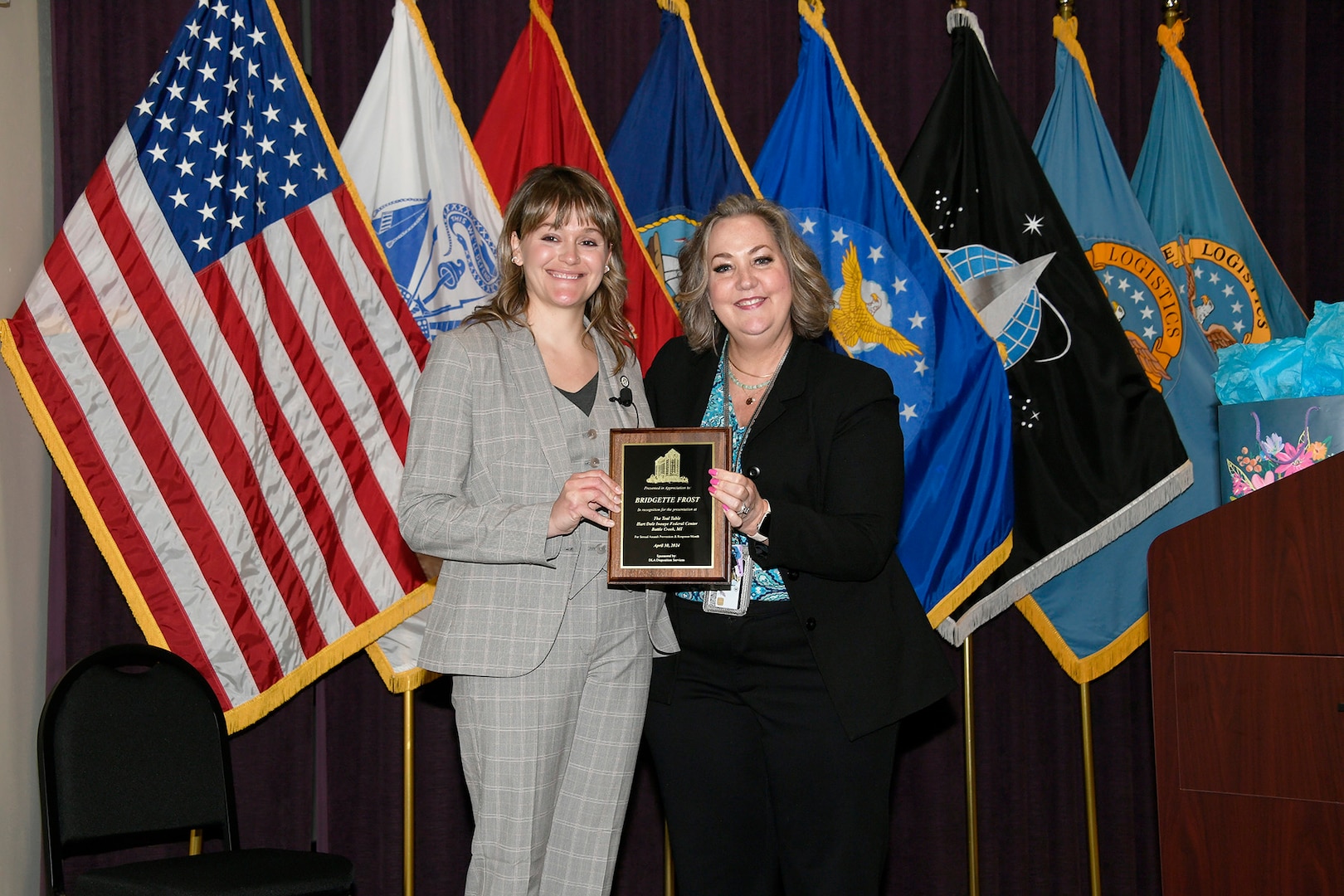 Female presenting plaque to another female.