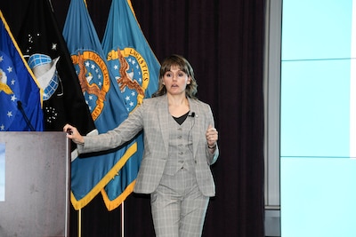 Female standing at podium speaking to an audience.