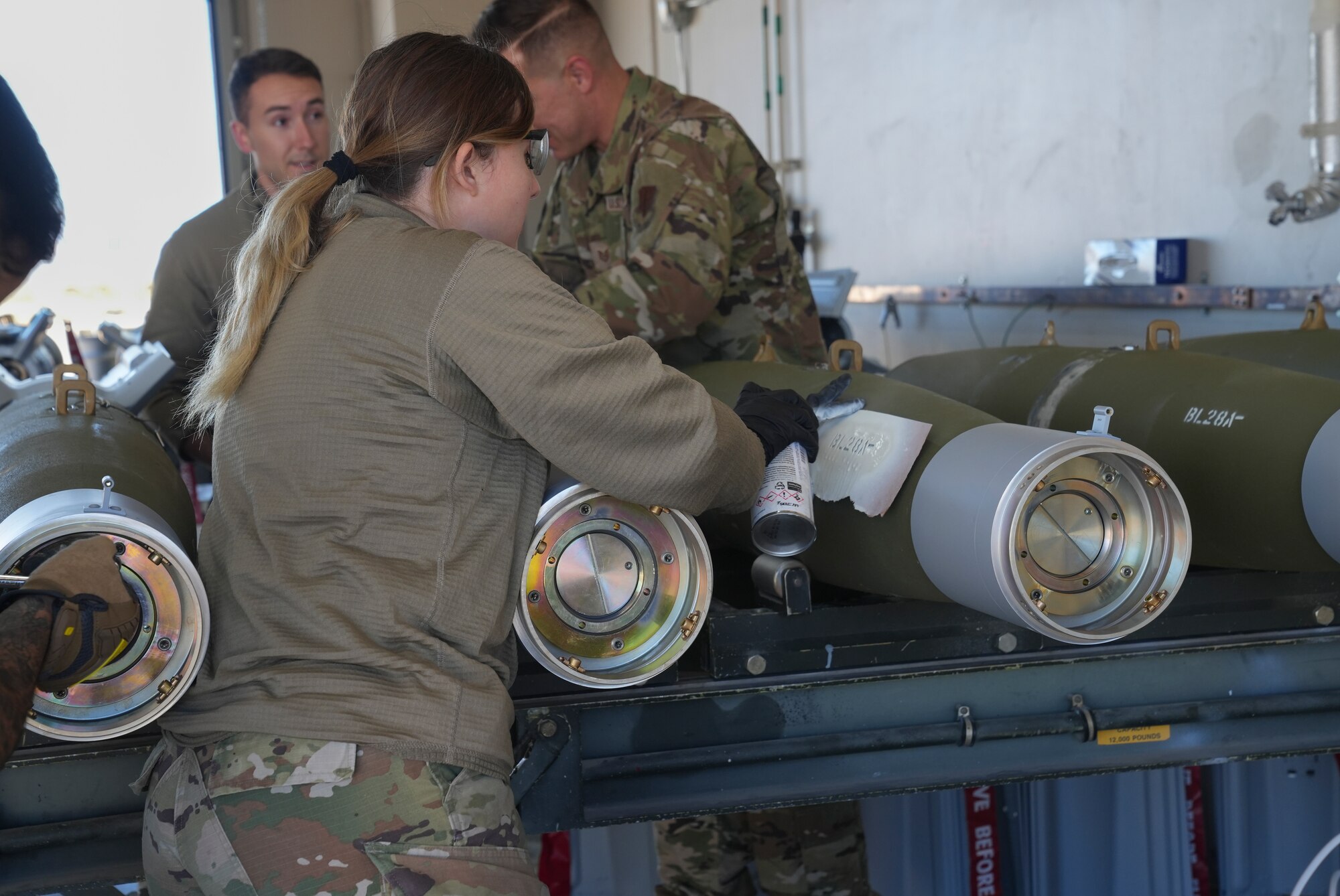 An airman spray painting a guided bomb unit/