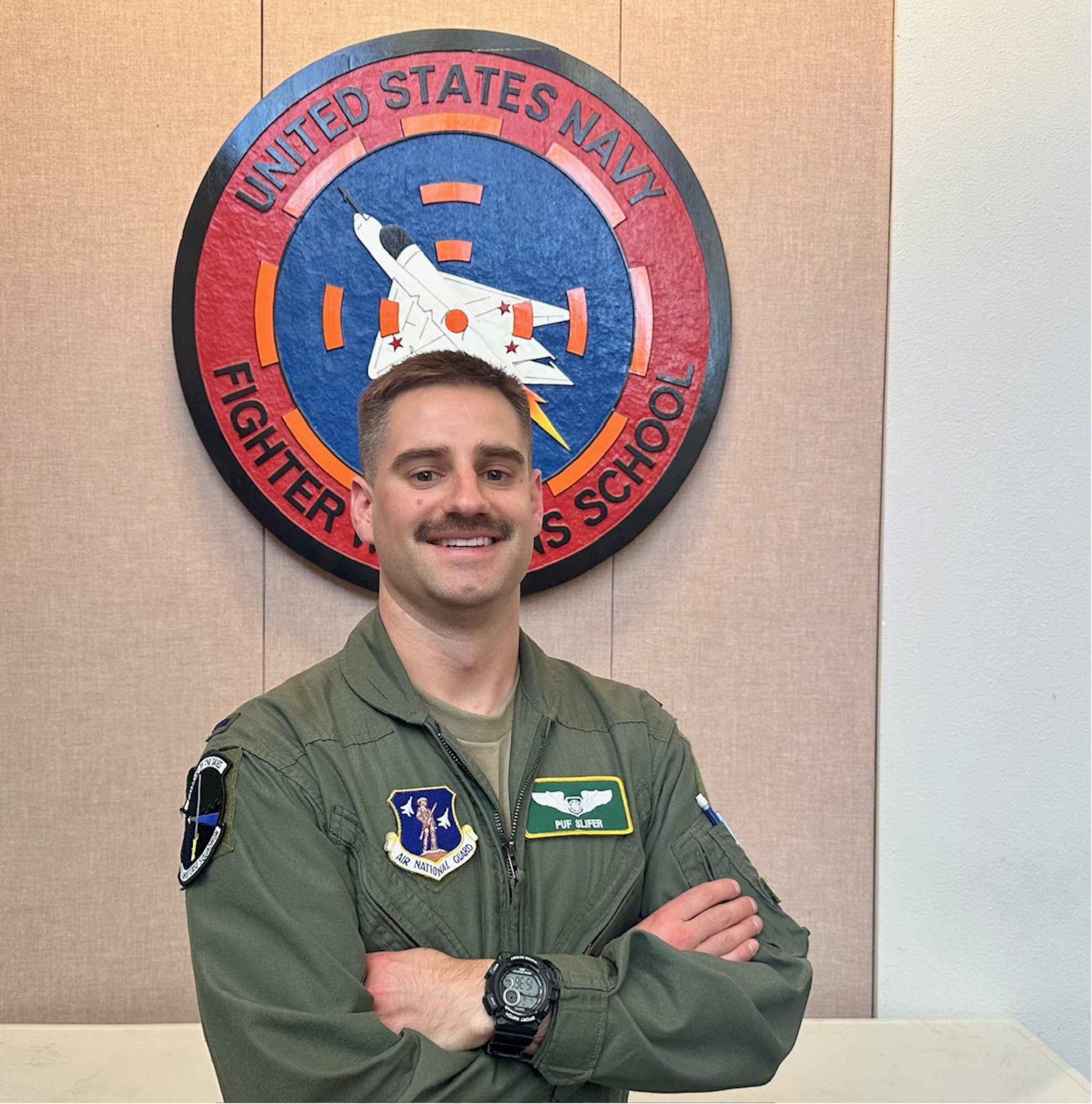 Airman poses in front of TOPGUN sign
