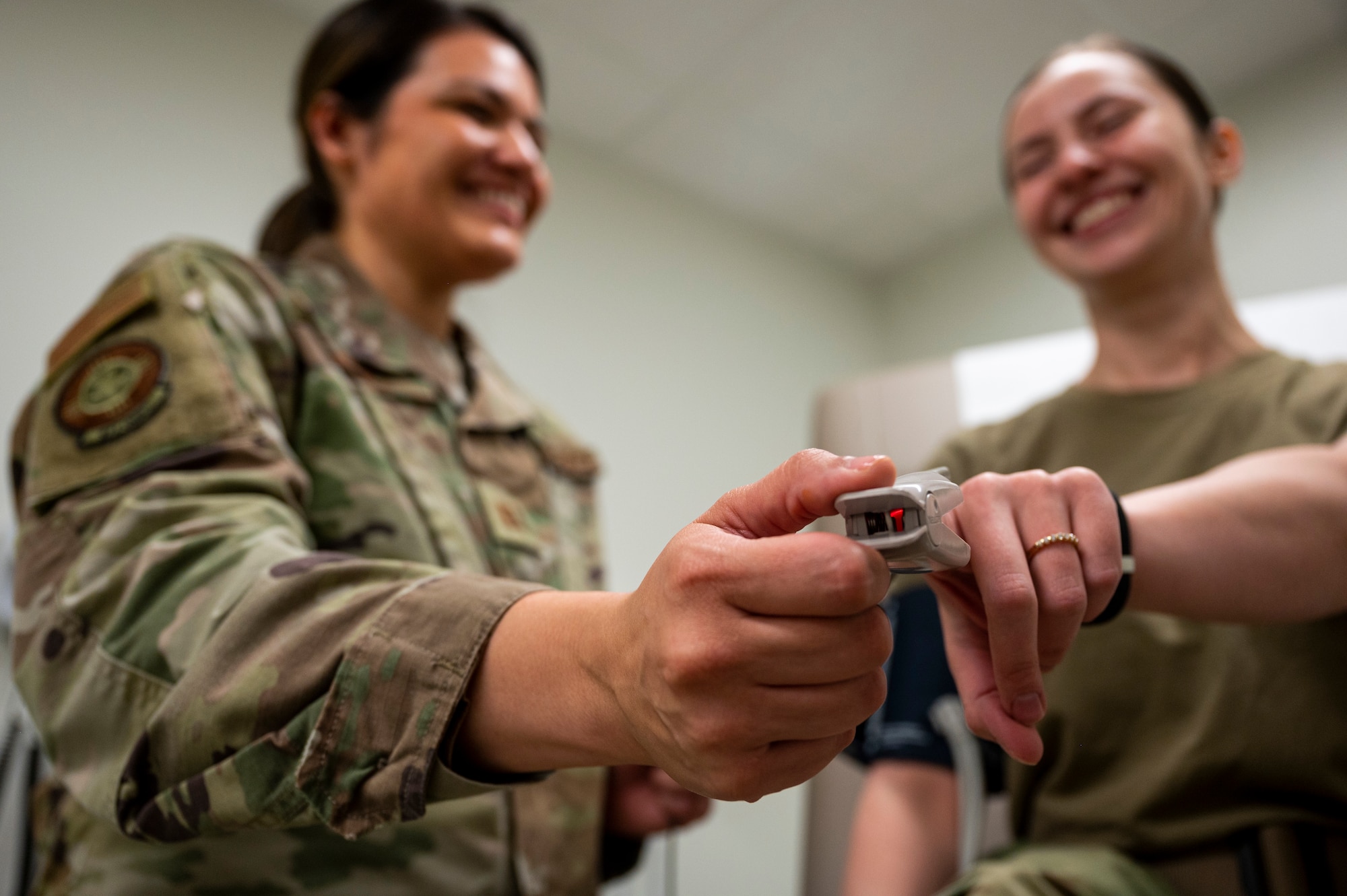 Woman places oximeter on finger of another woman.