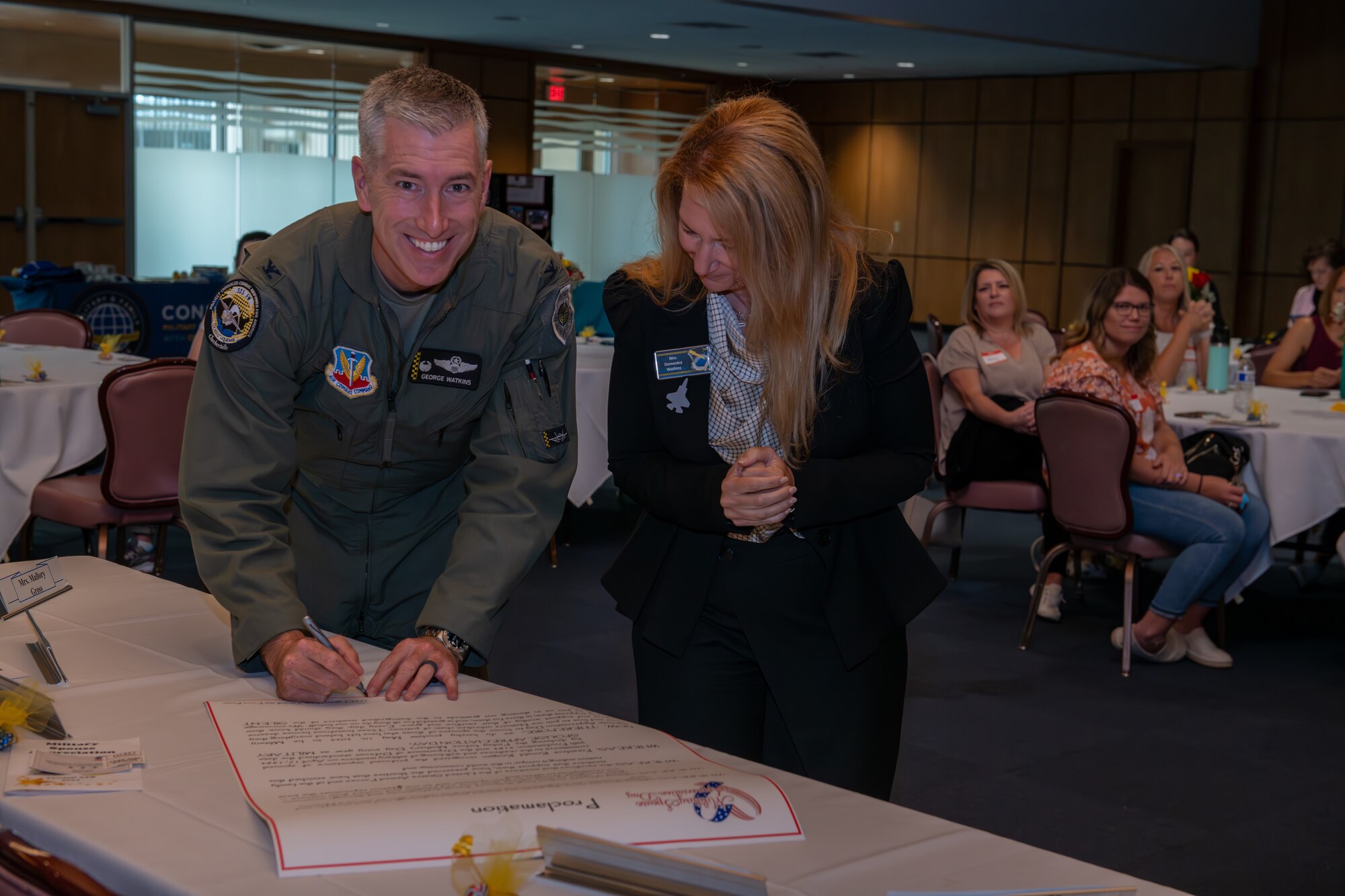 A man poses for a photo while signing a paper.