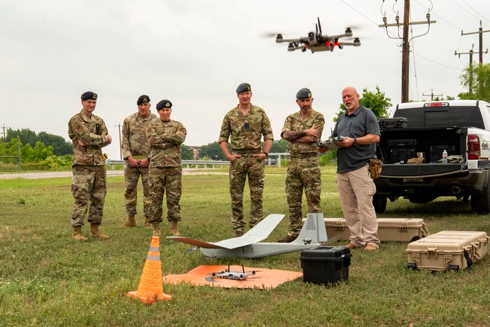 Five uniformed members watch while Adkins talks about a SUAS in the foreground.
