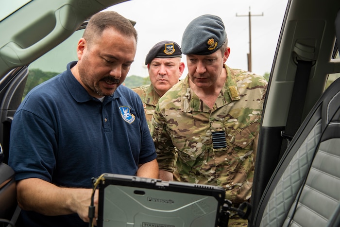 Three individuals looking at a screen in the front seat of a truck