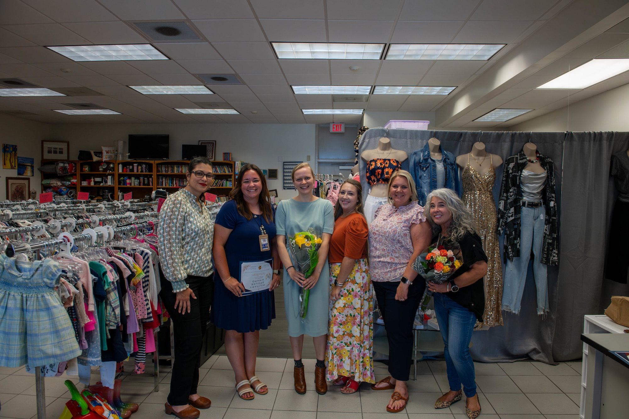 A group of women pose for a photo in a thrift shop.