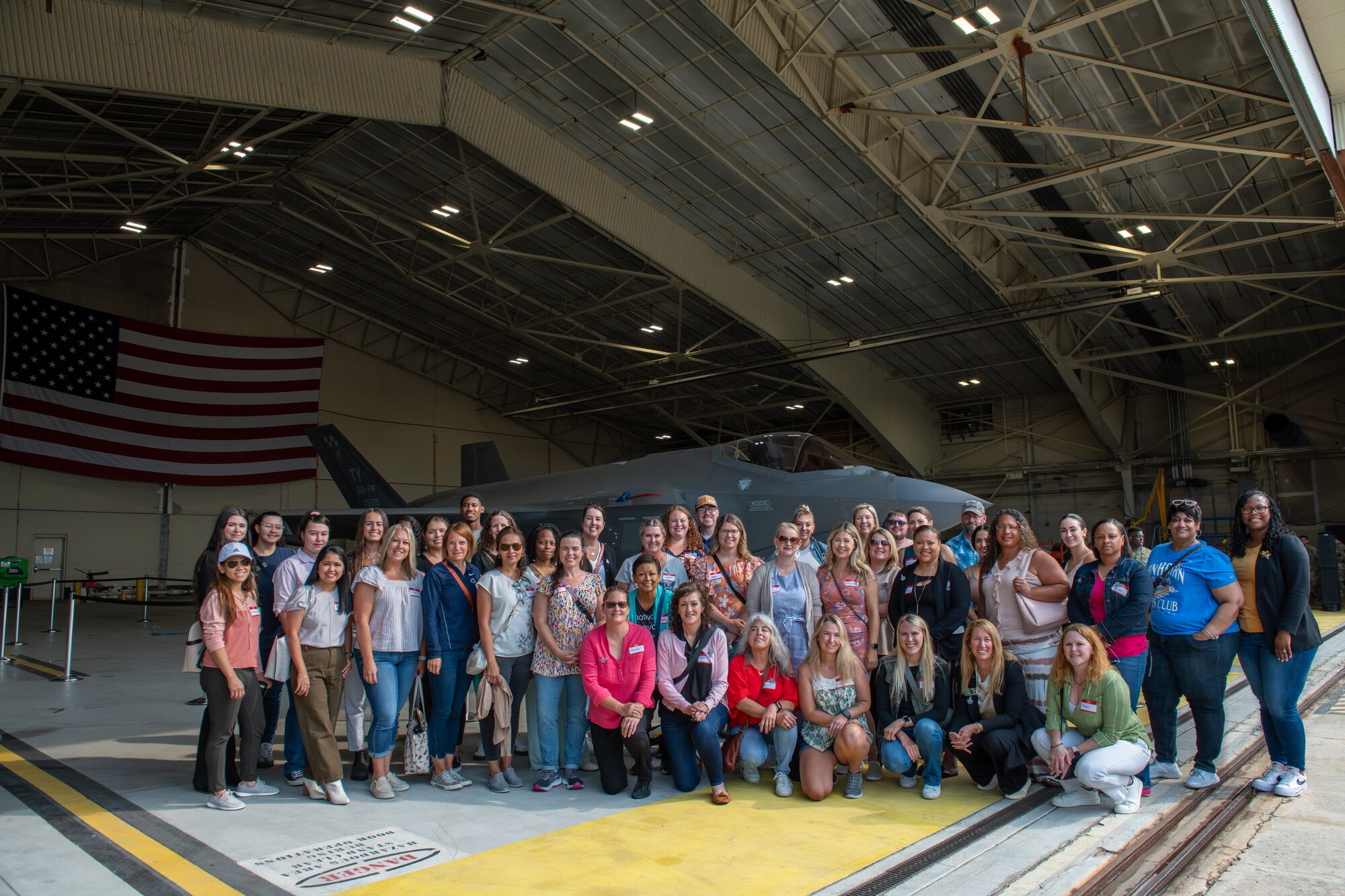 A group of people pose for a photo in front of a fighter jet