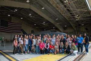 A group of people pose for a photo in front of a fighter jet