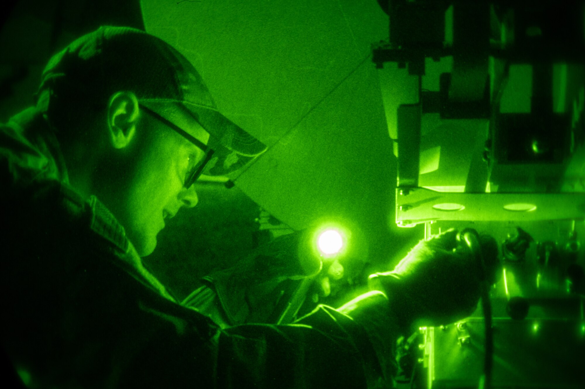 Night vision photo of a U.S. Air National Guard Airman working on a satellite receiver dish.