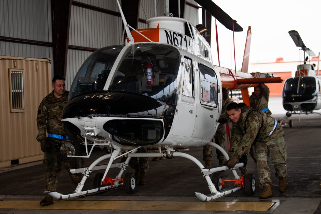 Airmen move a helicopter onto the flight line.