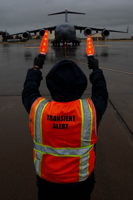 Service agent directs aircraft on flight line in the rain