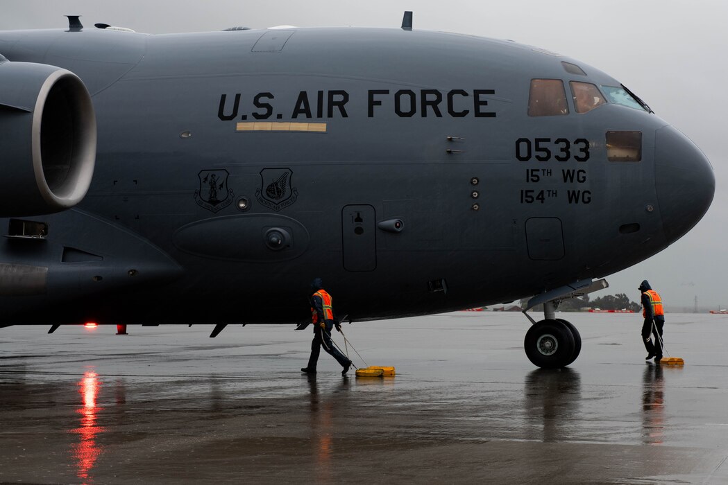 Service agents place chocks on aircraft in the rain