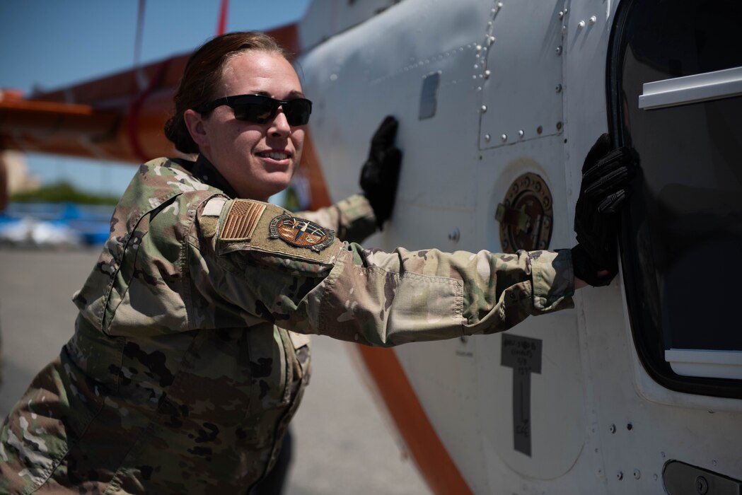 Airman helps stir the movement of a helicopter on the flight line.