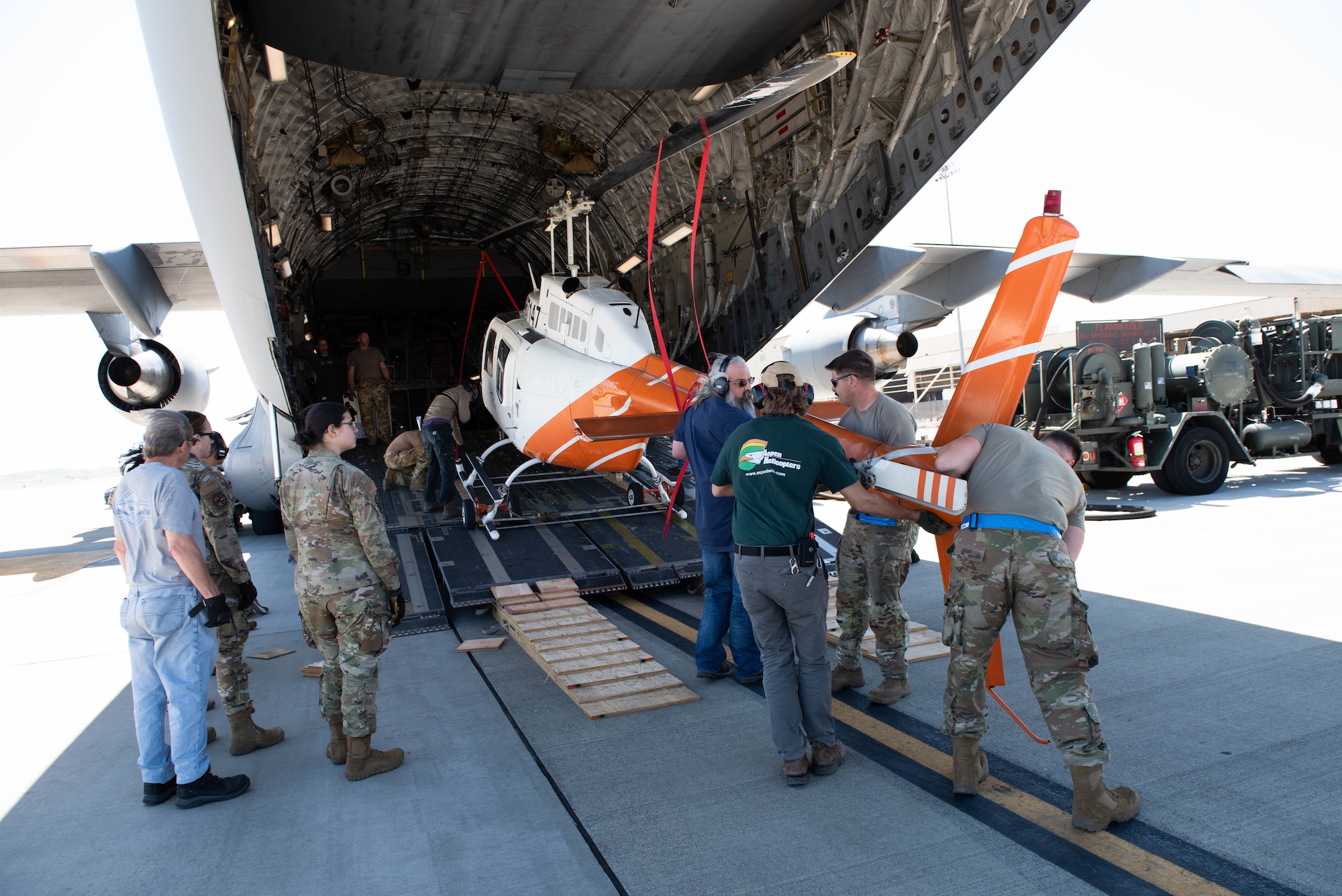 Airmen maneuver helicopter into larger aircraft