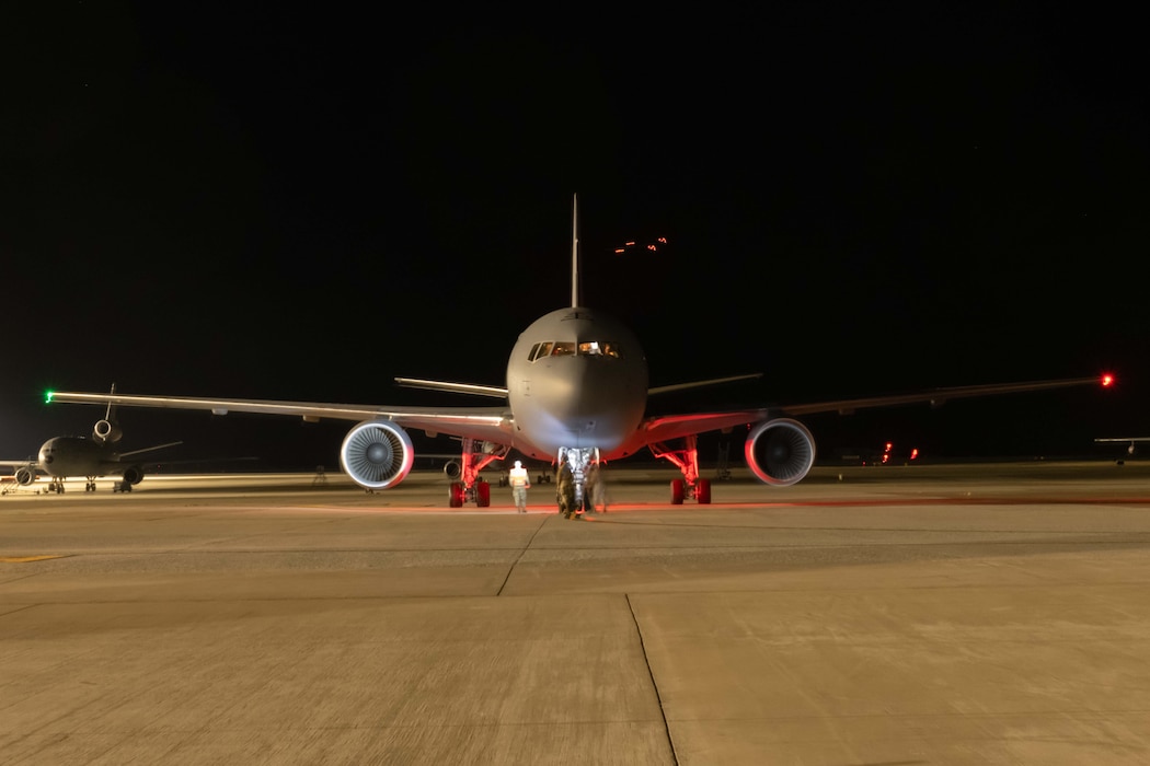 A KC-46A Pegasus aircraft sits on the flightline at night