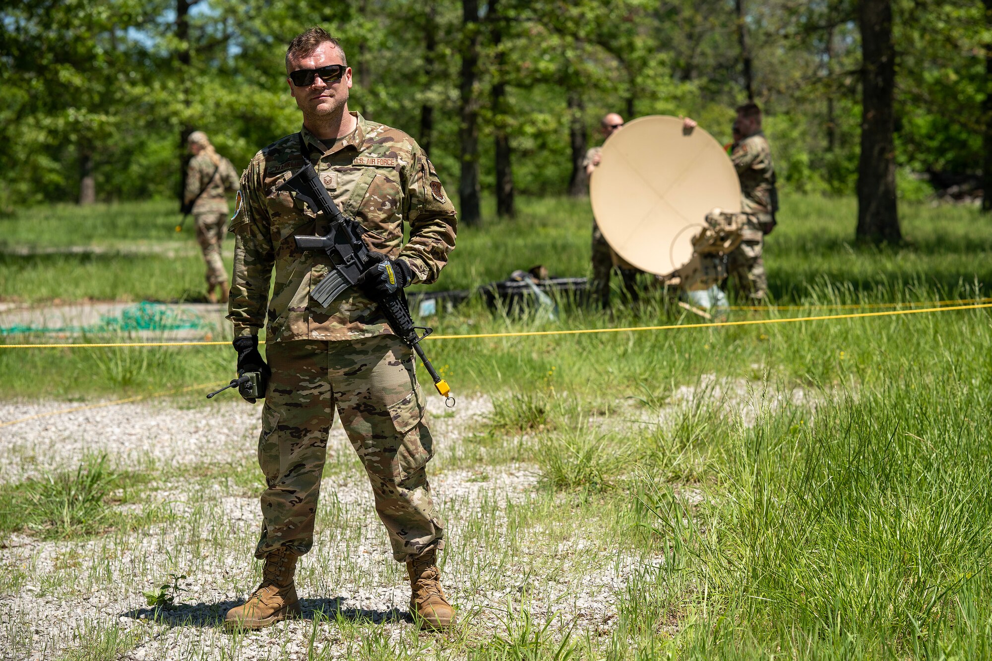 A U.S. Air National Guard Airman stands guard in front of a portable satellite receiver.