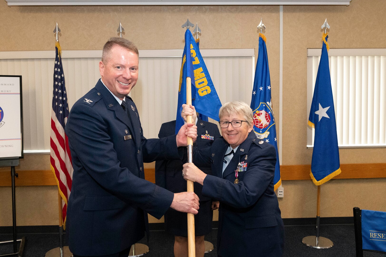 a man and woman grip the pole of a unit flag