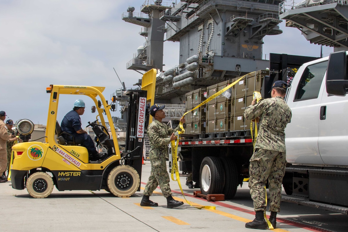 Sailors load ammunition onto a ship.
