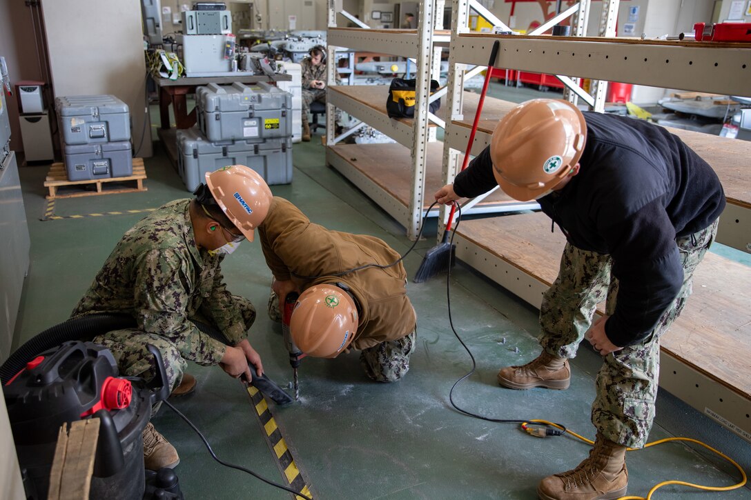 U.S. Navy Seabees with Headquarters & Headquarters Squadron, Marine Corps Air Station Iwakuni, drill into the floor to install shelving anchors at MCAS Iwakuni, Japan, March 22, 2024. The Seabees of MCAS Iwakuni are able to complete a variety of construction tasks, from installing furniture to repairing the airfield. (U.S. Marine Corps photo by Lance Cpl. Colin Thibault)