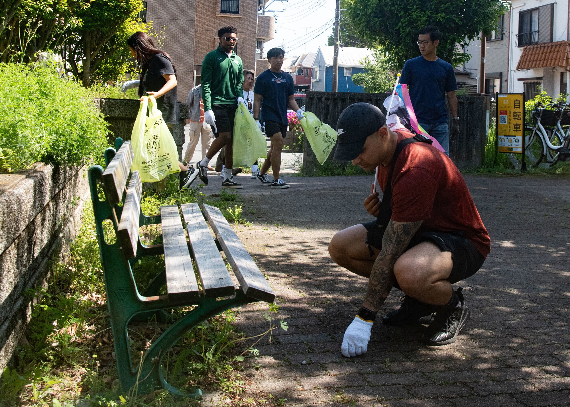 A participant picks up a piece of garbage while others look for litter in the background.