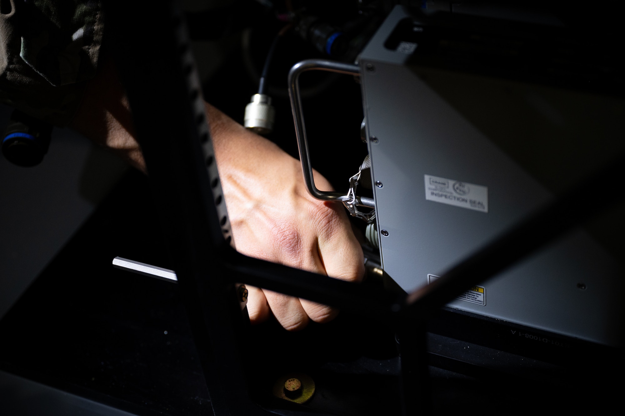 A hand is seen attaching a cable to a box.