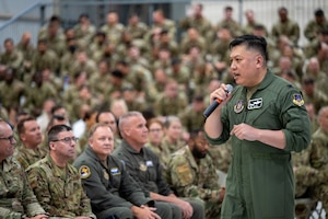 U.S. Air Force Col. Van T. Thai, 434th Air Refueling Wing commander, delivers remarks in a flight uniform to a crowd of military members in various U.S. Air Force uniforms.