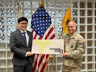 Army Soldier in uniform presents tuition check to future Army Medicine Professional