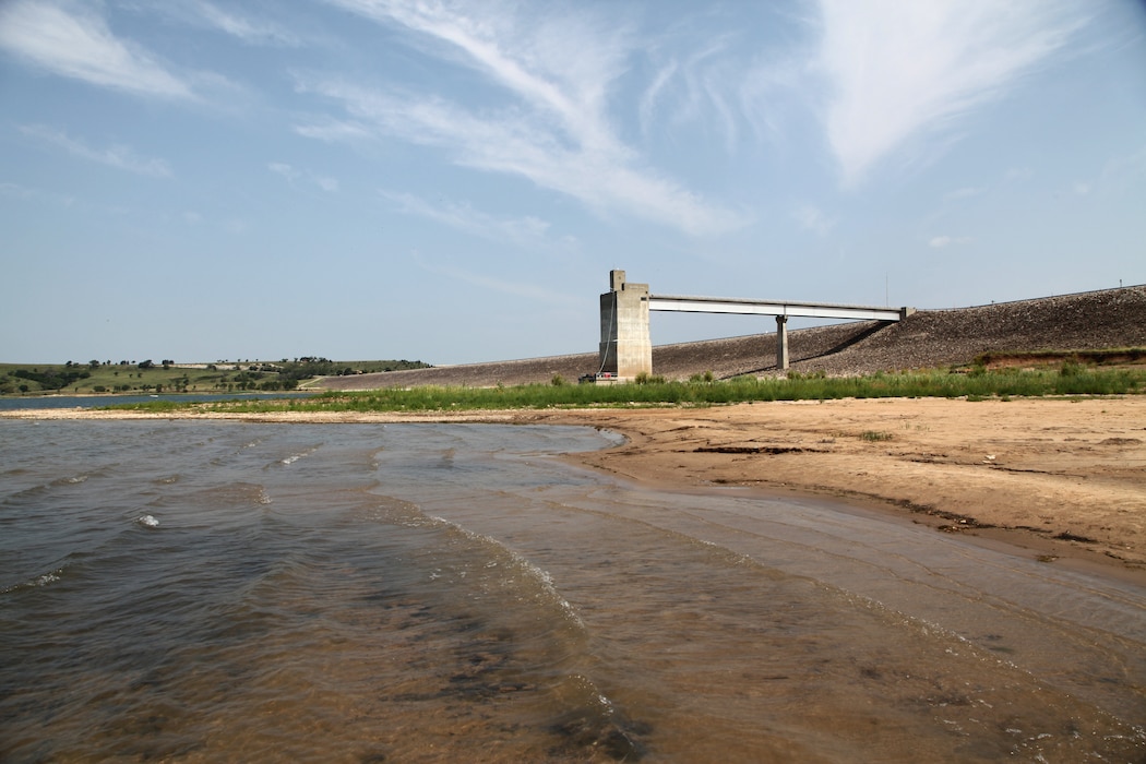 A lake with a concrete structure and sky in the background.