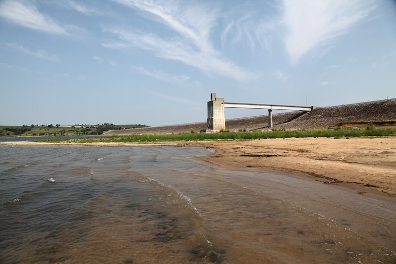 A lake with a concrete structure and sky in the background.