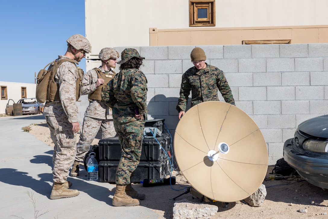 U.S. Marine Corps Pfc. Jacob Brandt, a Lewis Center, Ohio native, student with Marine Corps Communication-Electronics School, Training and Education Command, right, explains satellite antenna set ups to officer students during Basic Communications Officer Course 1-24 at Range 800, Marine Corps Air-Ground Combat Center, Twentynine Palms, California, April 30, 2024. During the BCOC students learn about signal modulation, basic electrical concepts and how to build field expedient antennas. (U.S. Marine Corps photo by Lance Cpl. Anna Higman)