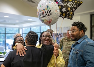 A graduate hugs their loved ones.