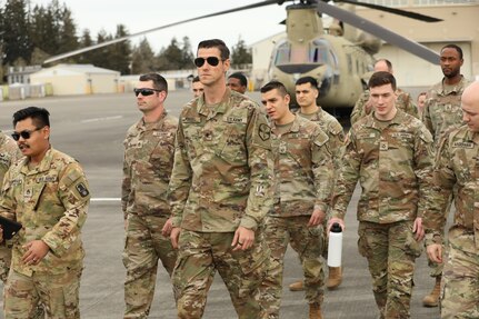 A group of soldiers walking past CH-47 Chinook helicopters.