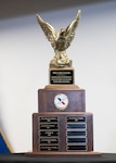 A mid-size trophy with a wooden base, ten small plaques, and a golden eagle on top