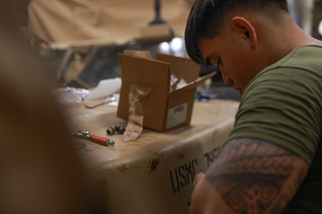 U.S. Marine Corps Sgt. Charles Gutierrez, an automotive maintenance technician assigned to Headquarters and Service Company, Battalion Landing Team 1/5, 15th Marine Expeditionary Unit, and a native of the Philippines, unboxes parts for a Joint Light Tactical Vehicle attached to BLT 1/5, 15th MEU, while working aboard the amphibious transport dock USS Somerset (LPD 25) in the South China Sea May 10, 2024. BK 24 is an annual exercise between the Armed Forces of the Philippines and the U.S. military designed to strengthen bilateral interoperability, capabilities, trust, and cooperation built over decades of shared experiences. (U.S. Marine Corps photo by Cpl. Aidan Hekker)