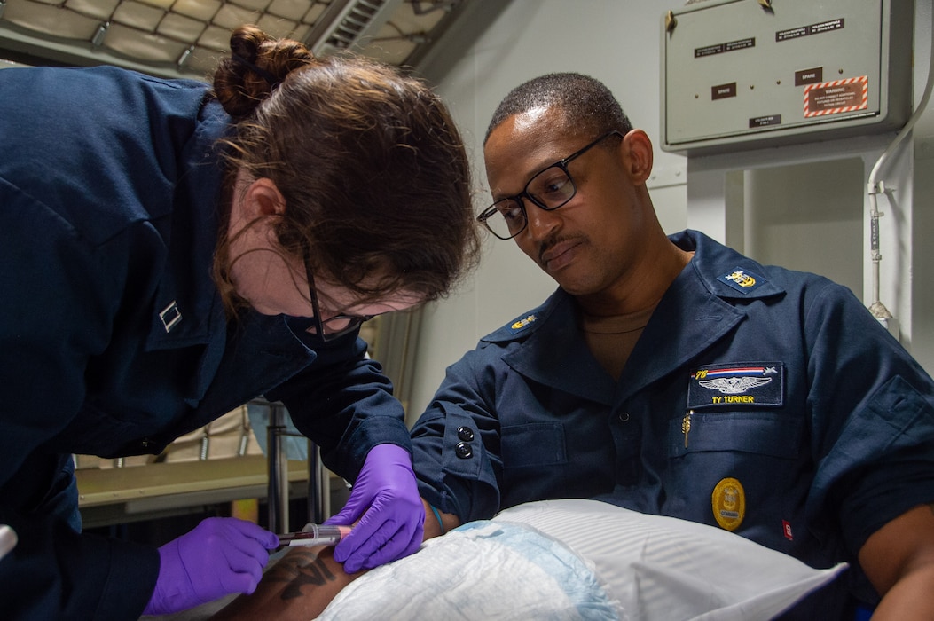 240510-N-UF592-1196 PHILIPPINE SEA (May 10, 2024) Command Master Chief Tychicious Turner, command master chief of the U.S. Navy’s only forward-deployed aircraft carrier, USS Ronald Reagan (CVN 76), has his blood drawn by Lt. Elizabeth Casey, ship’s nurse, from Anniston, Alabama, in the ship’s medical clinic for a walking blood bank screening aboard the U.S. Navy’s only forward-deployed aircraft carrier, USS Ronald Reagan (CVN 76), in the Tokyo Inlet May 10. Ronald Reagan, the flagship of Carrier Strike Group 5, provides a combat-ready force that protects and defends the United States, and supports alliances, partnerships and collective maritime interests in the Indo-Pacific region. (U.S. Navy photo by Mass Communication Specialist 3rd Class Eric Stanton)