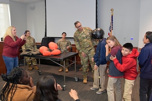 Staff Sgt. Jonathan Tuckwell, 388th Operations Support Squadron, assists visiting students with trying on an F-35 helmet, during a tour given to 120 students and faculty from North Davis Preparatory Spanish Academy May 8, 2024, at Hill Air Force Base, Utah. The tour was part of the Air Force’s Rated Diversity Improvement Strategy, called Project Quesada, which aims to identify opportunities for Air Combat Command units to partner with Hispanic- and other minority-serving institutions to inspire students in science, technology, engineering, and math. The tour was hosted by Hill’s Hispanic Heritage Committee. (U.S. Air Force photo by Todd Cromar)