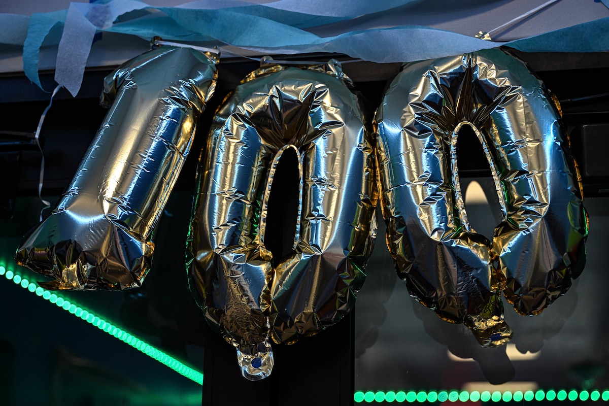 Balloons spelling out “100” hang over a door
