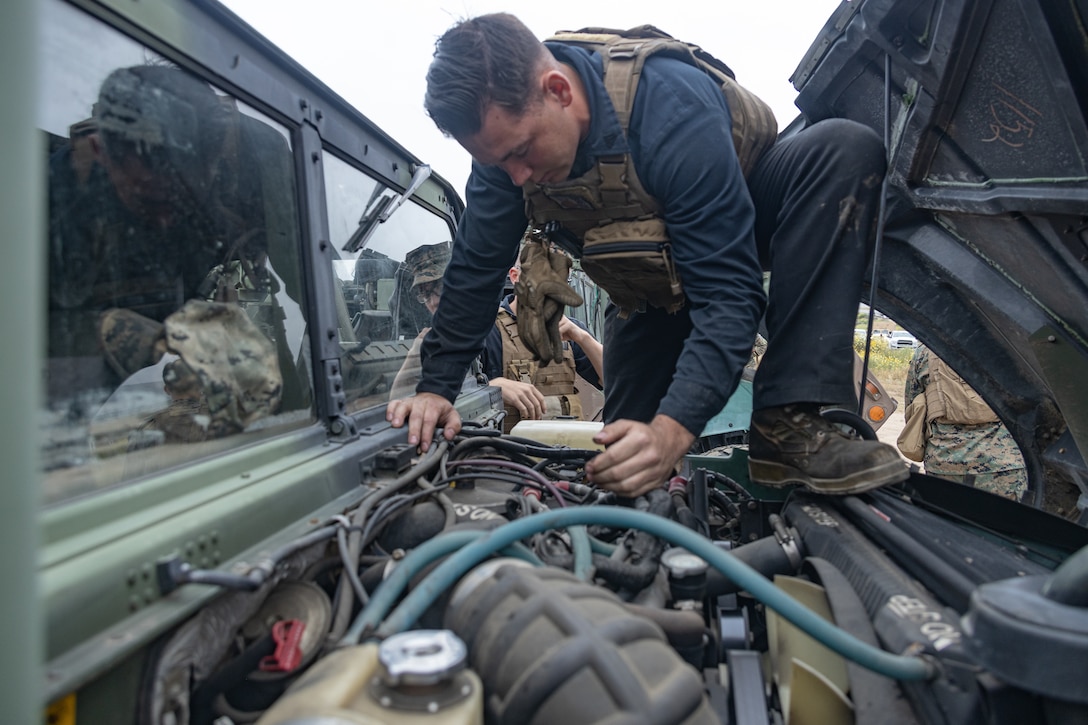 U.S. Marine Corps Cpl. Noah Holloway, an automotive maintenance technician with 9th Communication Battalion, I Marine Expeditionary Force Information Group, does a preventative maintenance check on a high mobility multipurpose wheeled vehicle during a battalion tactical road march, at Marine Corps Base Camp Pendleton, California, May 9, 2024. Cpl. Holloway is a Florida Native. The convoy served as training for the battalion to enhance convoy operations, validate equipment readiness, and sustain the unit’s operational readiness. (Marine Corps photo by Cpl. Ricardo Ramirez)