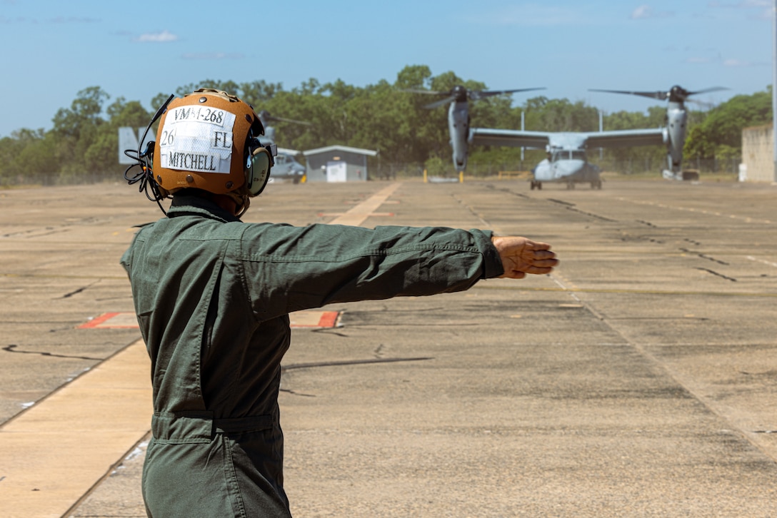 U.S. Marine Corps Cpl. Cyan Mitchell, a tiltrotor crew chief with Marine Medium Tiltrotor Squadron 268 (Reinforced), Marine Rotational Force – Darwin 24.3, directs MV-22B Ospreys down the flightline at Royal Australian Air Force Base Darwin, NT, Australia, May 11, 2024. The Ospreys were flown from Port Darwin to RAAF Base Darwin, where they will be hosted for the duration of the rotation. VMM-268 (Rein.) makes up the Aviation Combat Element, out of Marine Corps Air Station Kaneohe Bay, Hawaii, completing the structure of the MAGTF with the arrival of 10 MV-22B Ospreys. Mitchell is a native of Texas. (U.S. Marine Corps photo by Cpl. Juan Torres)