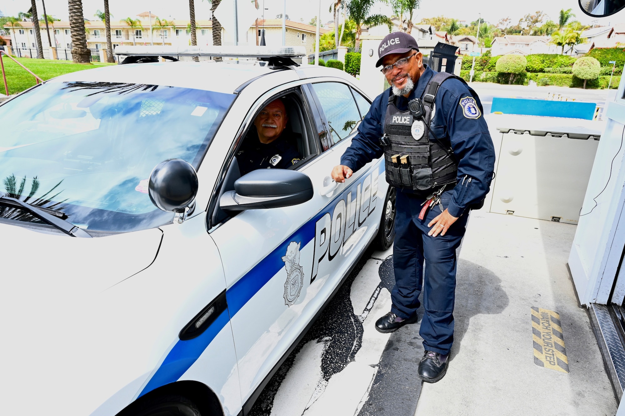 Officer Humphrey poses with another officer in a police vehicle at the Fort MacArthur main gate.