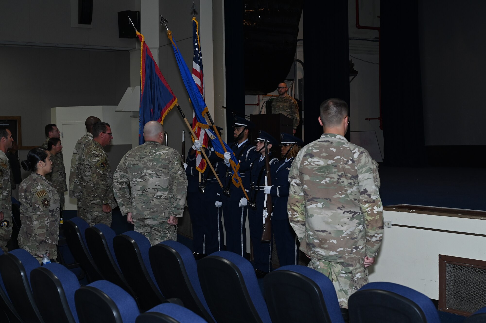 Airmen stand in attention in front of honor guard members holding the flags.