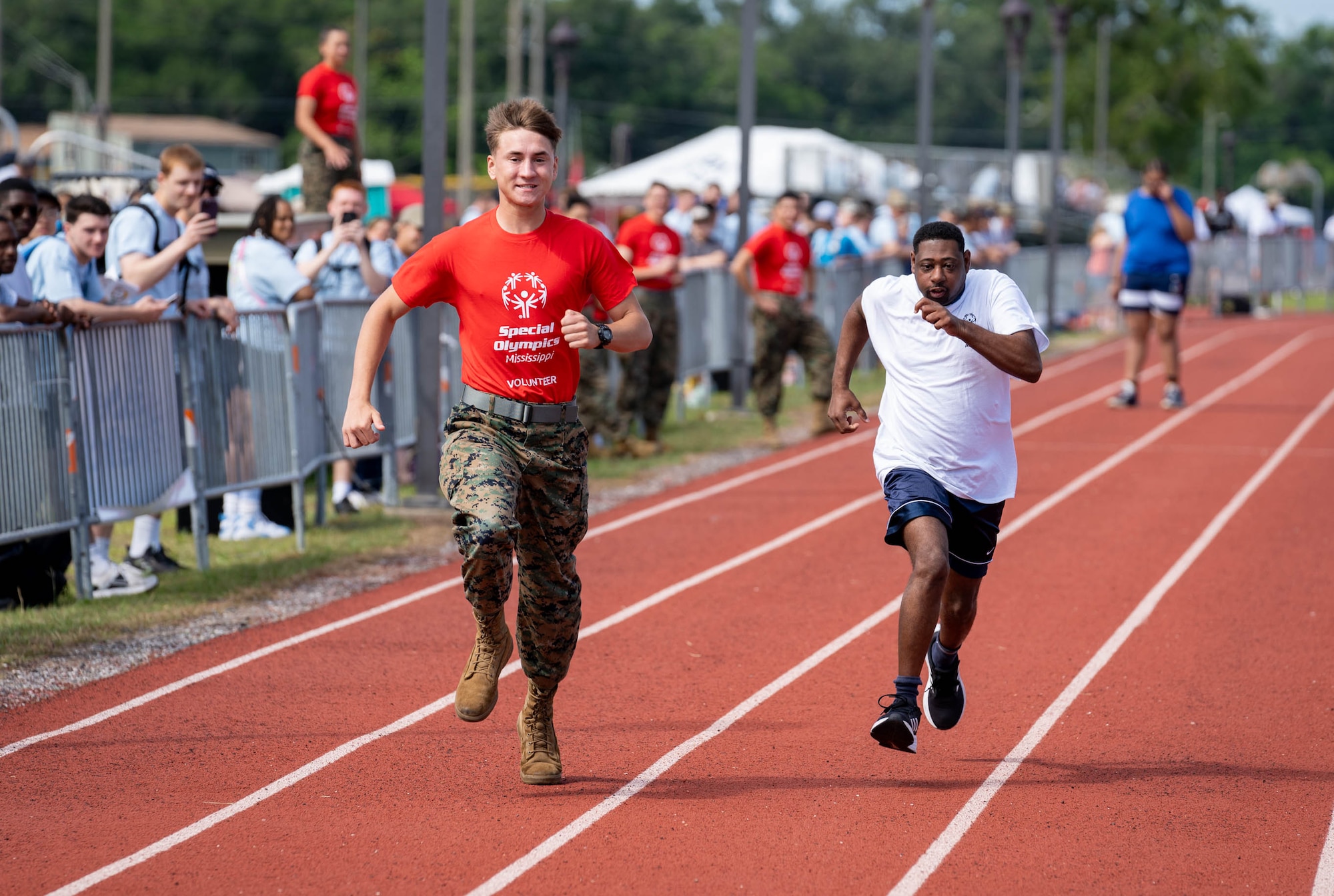 A Special Olympics Mississippi athlete races in a track and field event, encouraged by a student assigned to the Keesler Marine Detachment at Keesler Air Force Base, Mississippi, May 11, 2024.