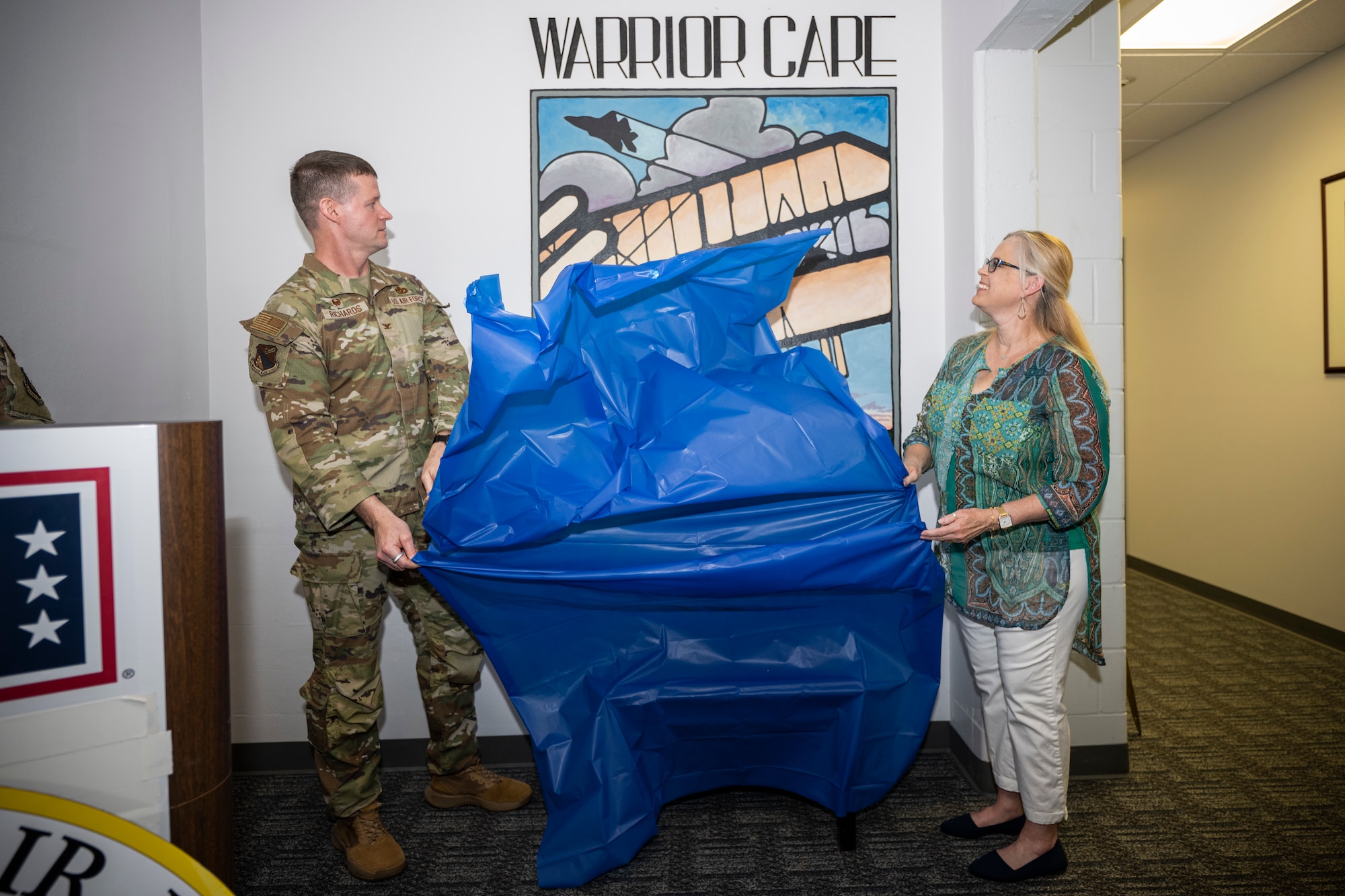 Col and civilian female unveil a mural.