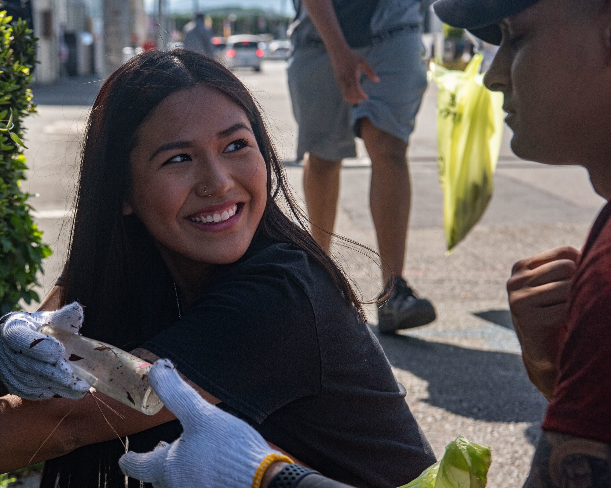 A participant smiles and hands a piece of litter to another participant.