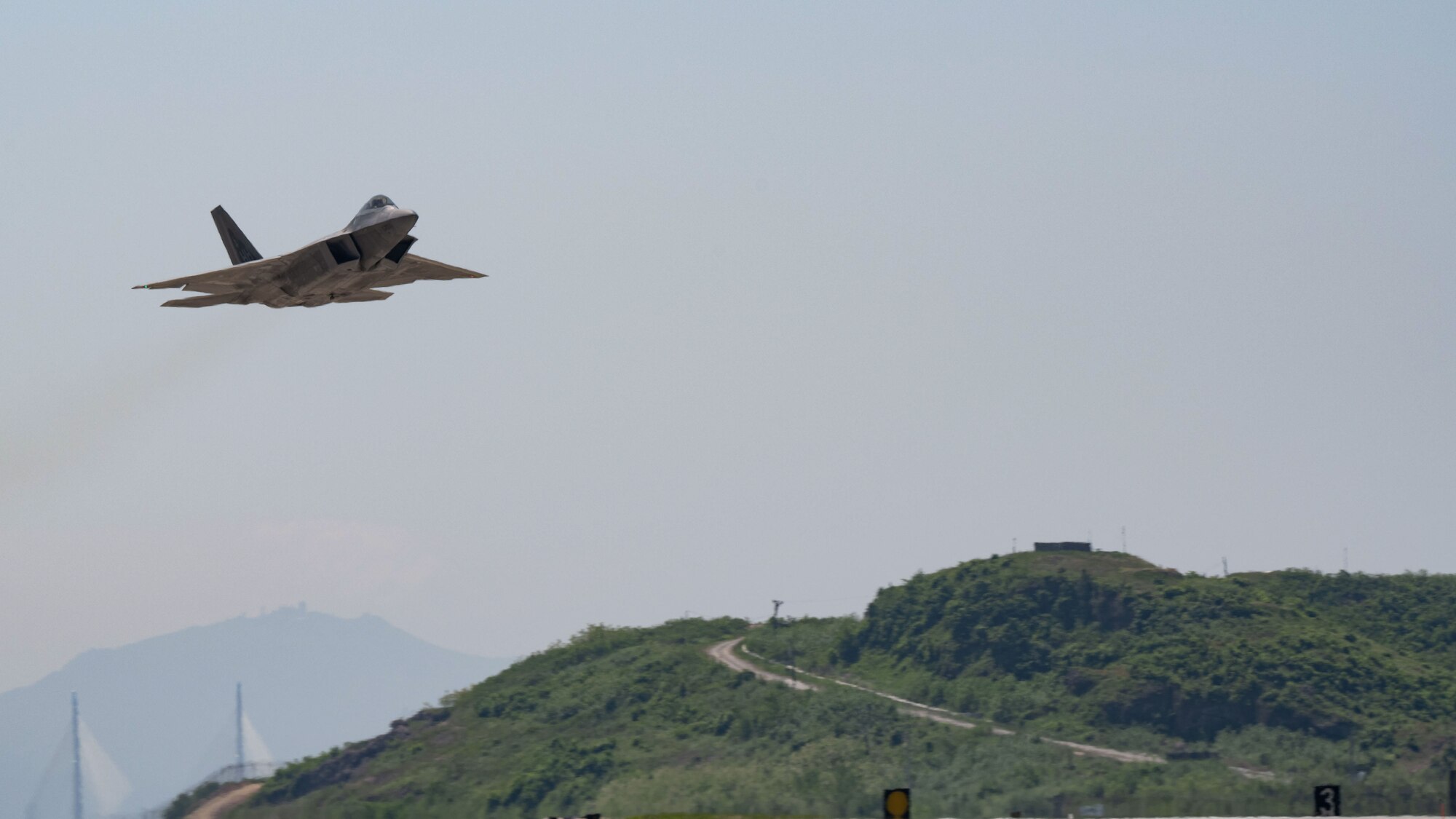 An F-22 Raptor, assigned to Joint Base Pearl Harbor-Hickam, flies over Kunsan Air Base.
