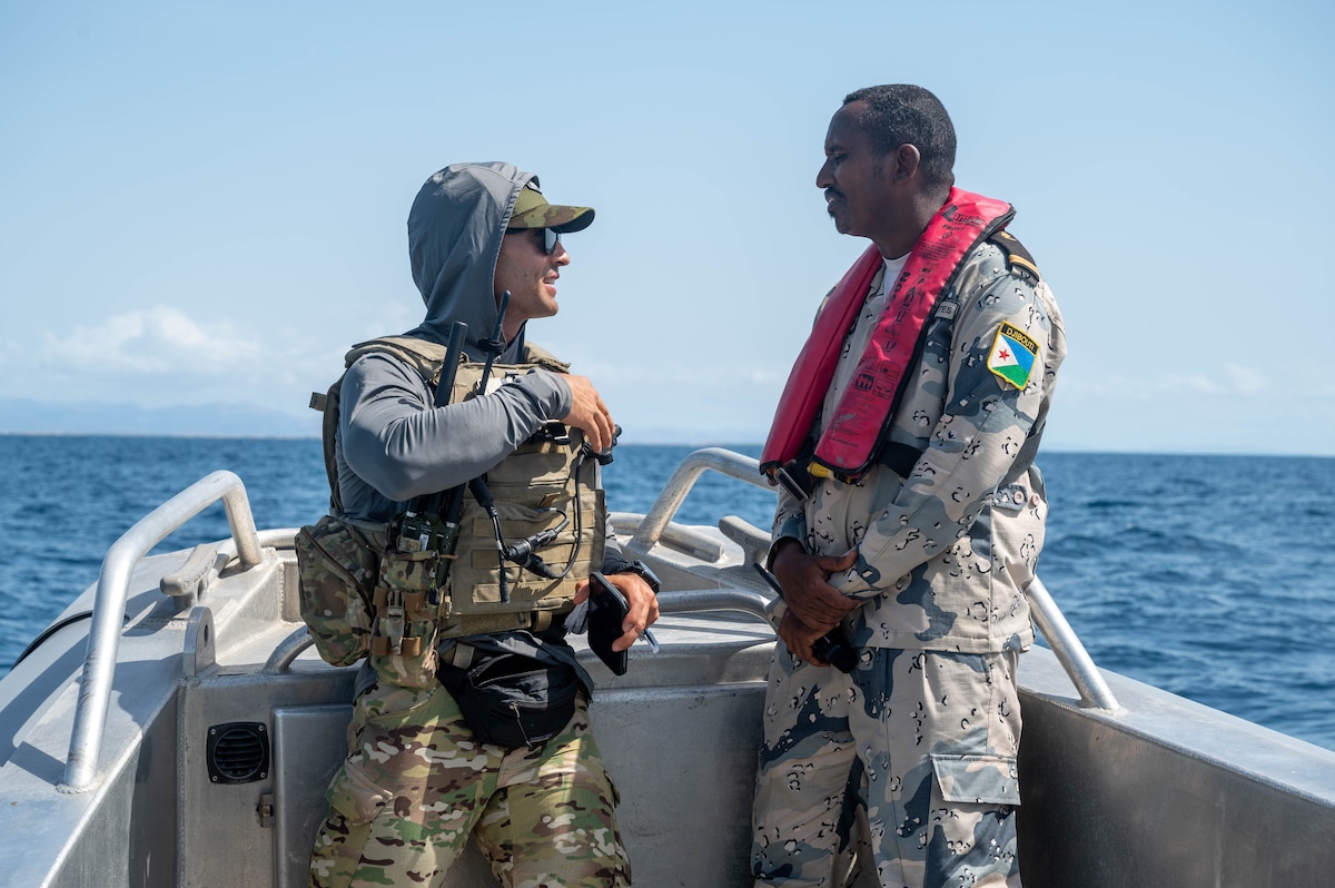 Two people smile during a conversation on board a boat.